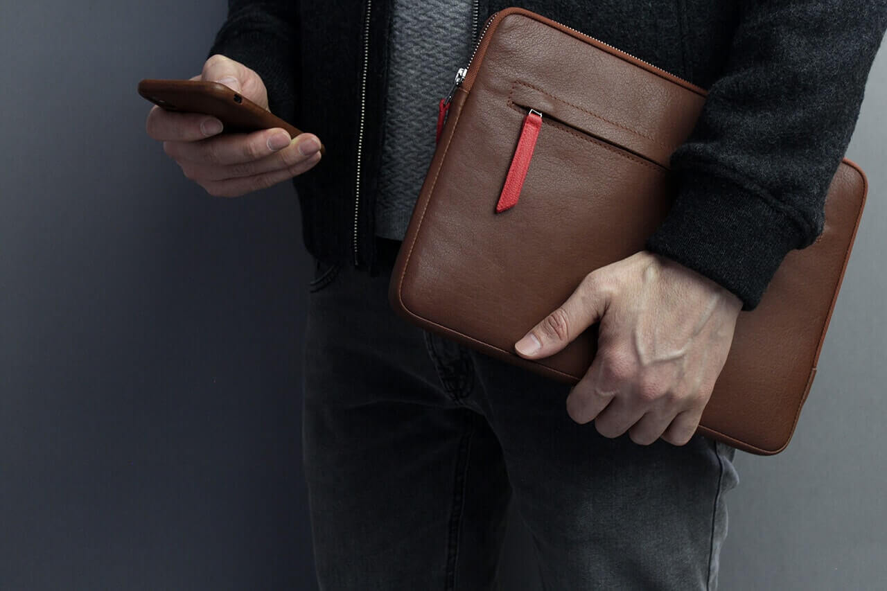 Mann hält eine Microsoft Surface Pro Hülle ANGUS aus Leder in dunkelbraun, perfekt für Surface Pro 11 / 10 / 9 / 8 / 7 / 6.