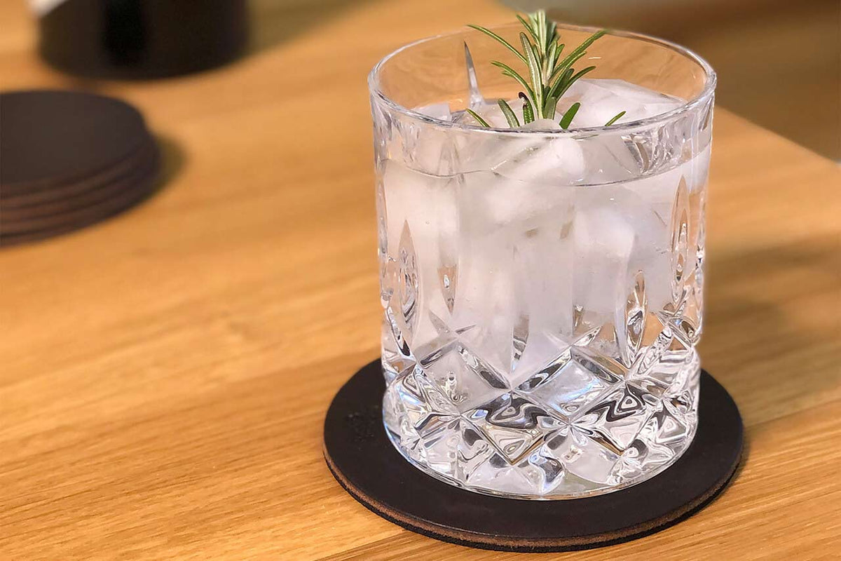Glas mit Eis und Rosmarin auf einem dunkelbraunen Glasuntersetzer aus Leder, Modell DEXTER