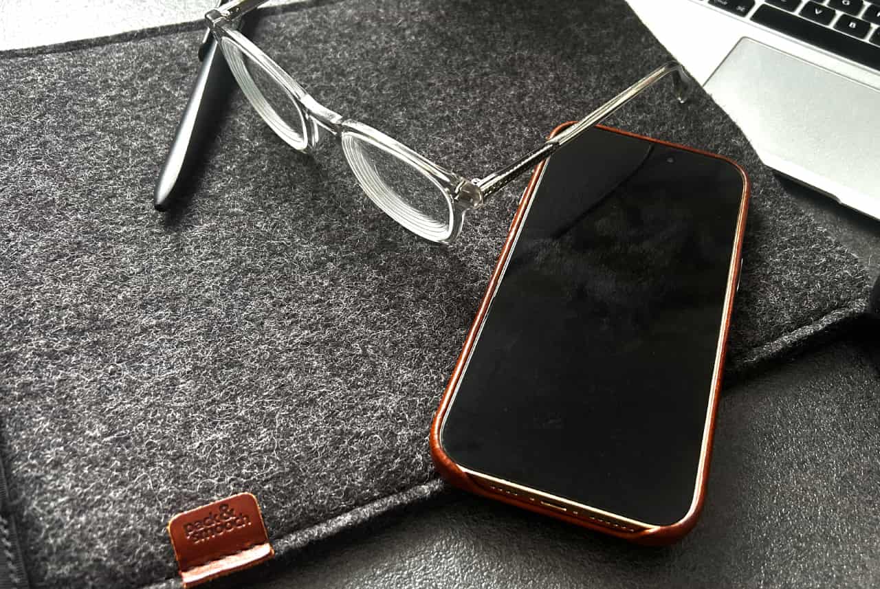 MacBook Hülle SUFFOLK aus Merino Wollfilz mit Brille und Smartphone auf grauem Filzuntergrund